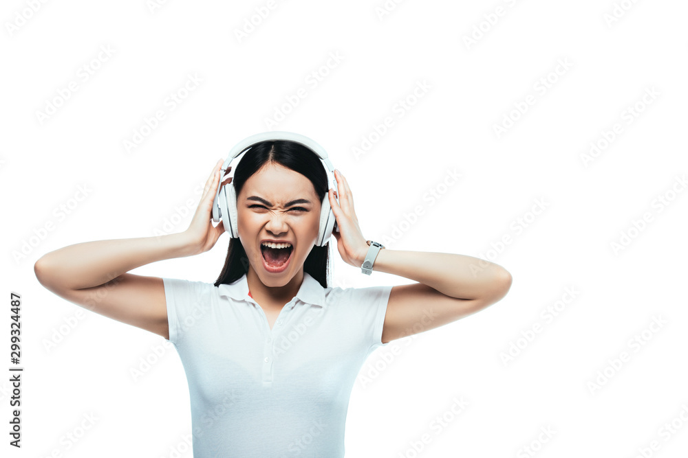 angry attractive asian girl screaming in headphones isolated on white angry attractive asian girl screaming in headphones isolated on white
