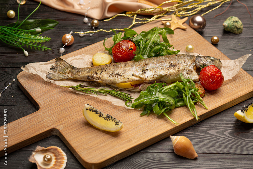 fried trout with arugula, cherry tomatoes and lemon on a board fried trout with arugula, cherry tomatoes and lemon on a board