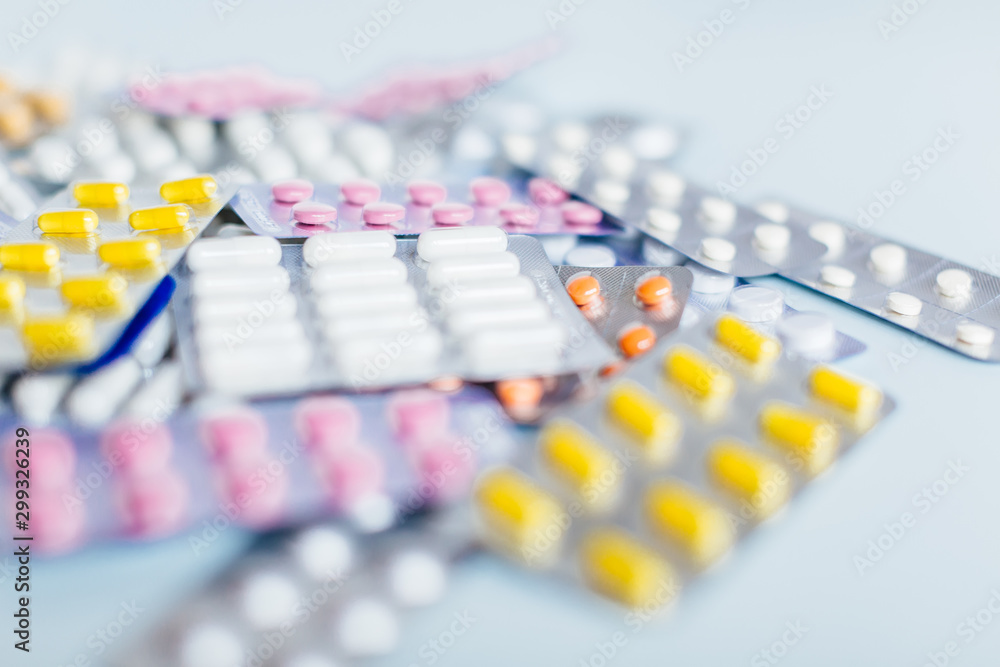 Naklejka premium Various medicaments: white, pink and yellow pharmaceutical medicine pills, a remedy for flu, headache pills, antibiotics. Medical and healthcare concept. Close up photo, selective focus.
