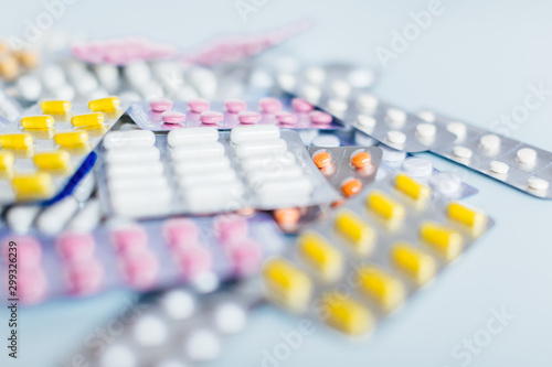 Various medicaments: white, pink and yellow pharmaceutical medicine pills, a remedy for flu, headache pills, antibiotics. Medical and healthcare concept. Close up photo, selective focus.