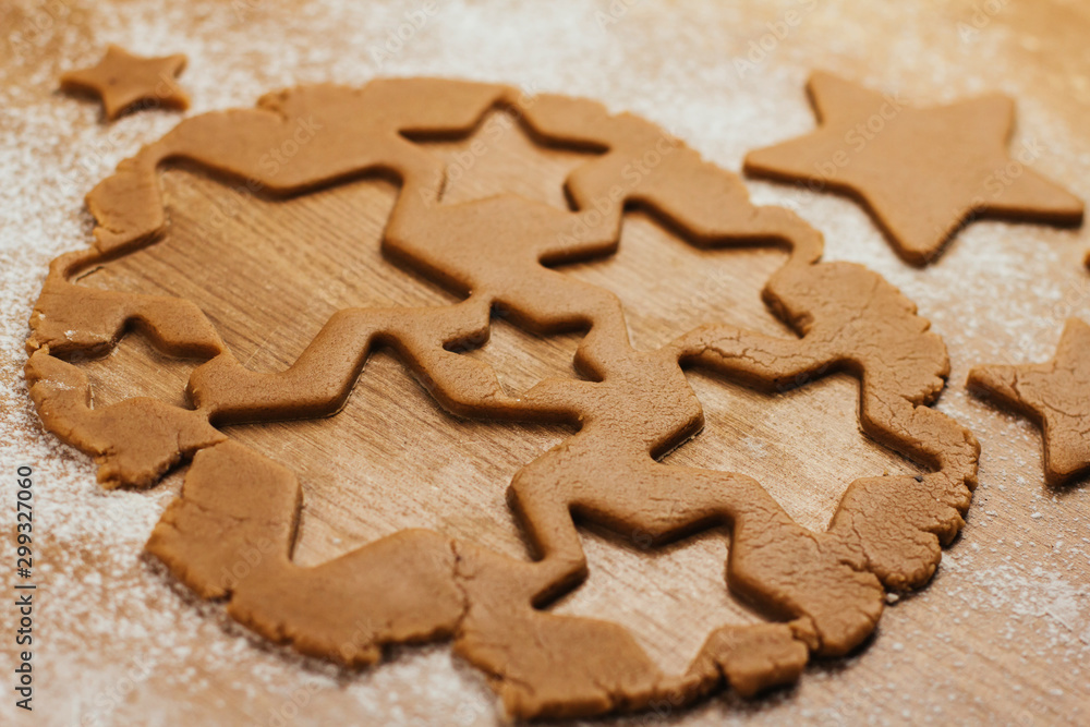 Dough for gingerbread cookies on a table sprinkled with flour. Cutting cookies in the shape of stars.	