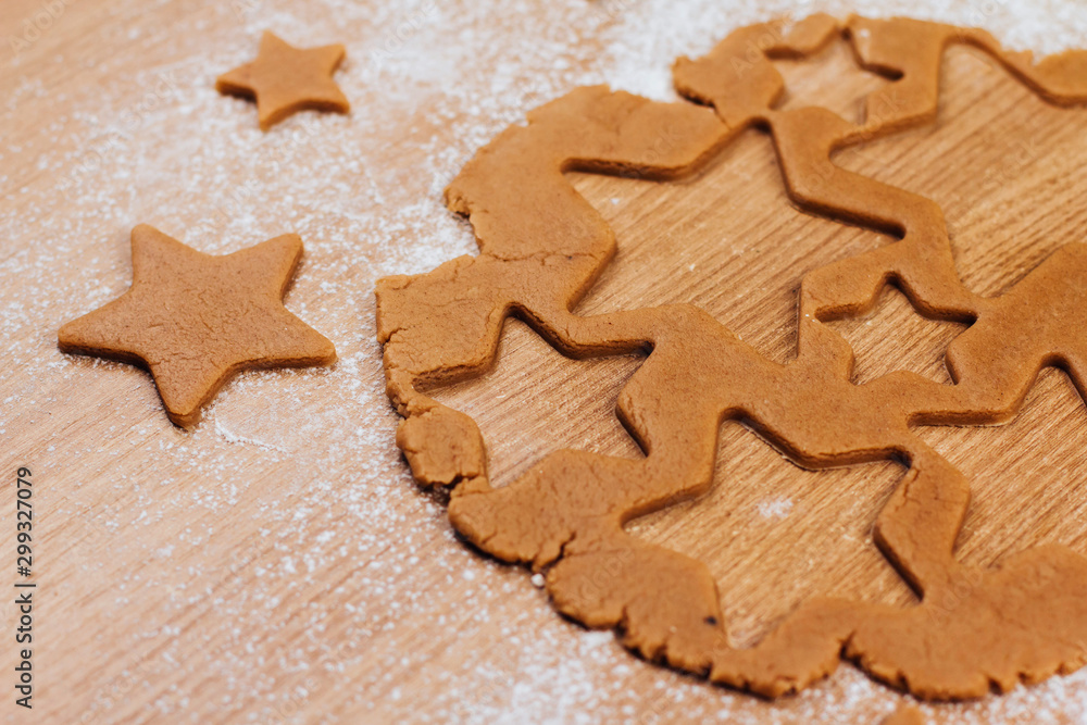  Dough for gingerbread cookies on a table sprinkled with flour. Cutting cookies in the shape of stars.