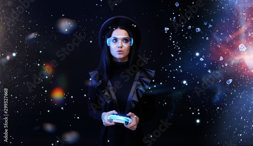 Beautiful woman with joystick in glasses of virtual reality on dark magic background. Augmented reality, future technology concept. VR. Futuristic 3d glasses with virtual projection. Blue neon light.