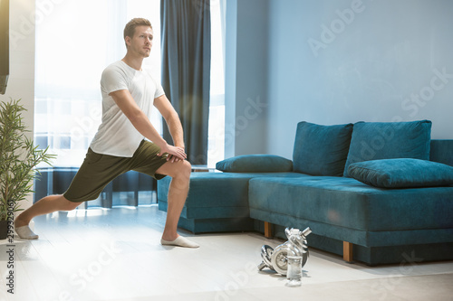 young handsome man doing lunges during workout at home looking focused sporty and healthy lifestyle