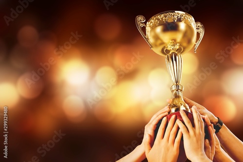Hands holding golden trophy on light background