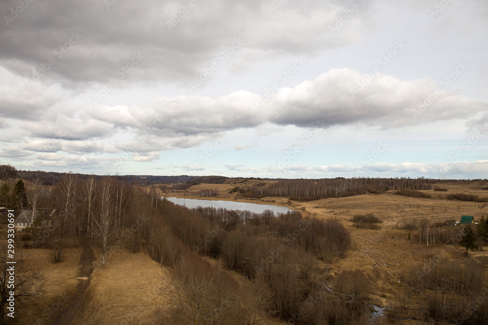 Panorama of the spring landscape with a lake and hills with copses. Izborsk, Pskov region, Russia.