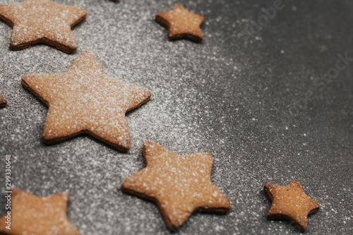  gingerbread cookies sprinkled with icing sugar on a dark gray background. Christmas baking.