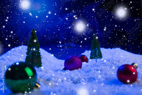 Christmas background with Christmas balls on snow over fir-tree, night sky and moon. Shallow depth of field. Christmas background. Fairy tale. Macro. Artificial magic dreamy world. © Alik Mulikov
