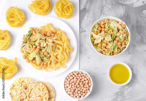 Vegetarian cuisine. Salad with chickpeas and cabbage, pasta, olive oil, crisp bread. Concrete background