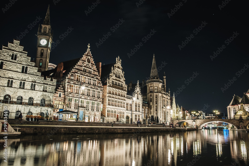 Panoramic view of Graslei in the historic city center of Ghent at night with reflections on the Leie river, Ghent, East Flanders, Belgium