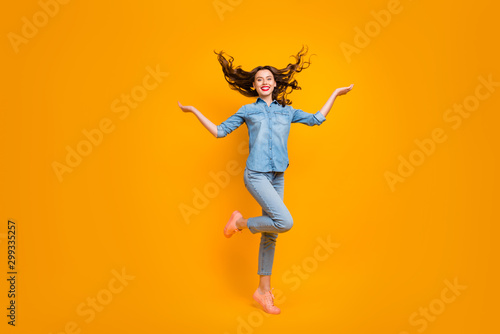 Full length body size photo of cheerful charming fascinating girl throwing her hair standing on one foot with positive facial expression isolated over yellow vivid color background photo