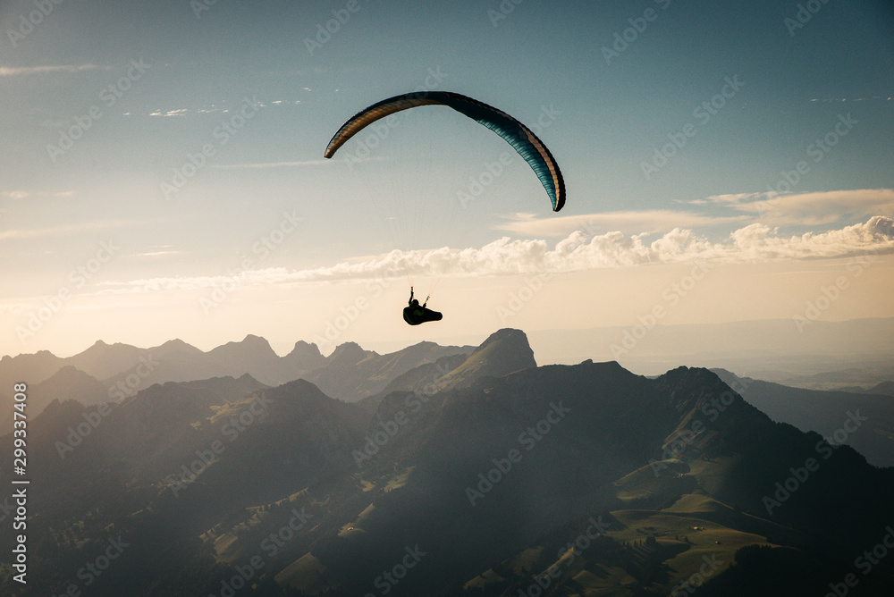 Person Paragliding im blauen Himmel gegen die Sonne Person Paragliding im blauen Himmel gegen die Sonne