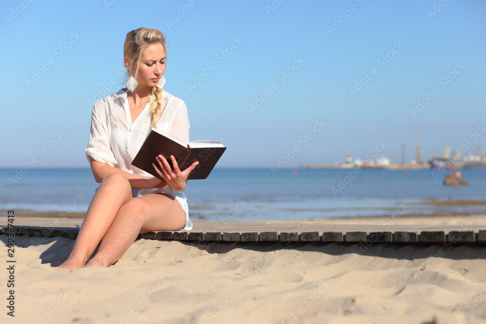 woman reads a book on the beach