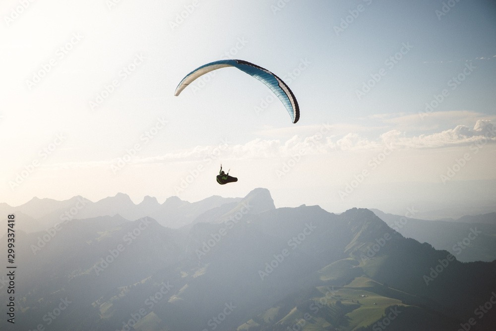 Person Paragliding im blauen Himmel gegen die Sonne Person Paragliding im blauen Himmel gegen die Sonne