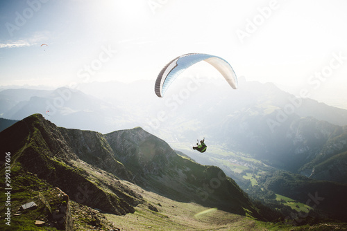 Person Paragliding im blauen Himmel gegen die Sonne photo