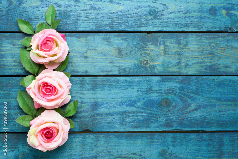 Wedding border with three pink rose flowers on blue wooden background Wedding border with three pink rose flowers on blue wooden background