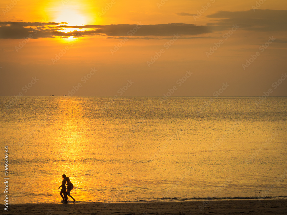 silhouette of a couple on beach at sunset in Thailand.