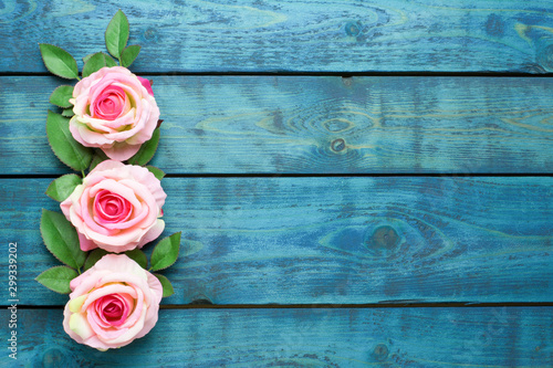 Wedding border with three pink rose flowers on blue wooden background