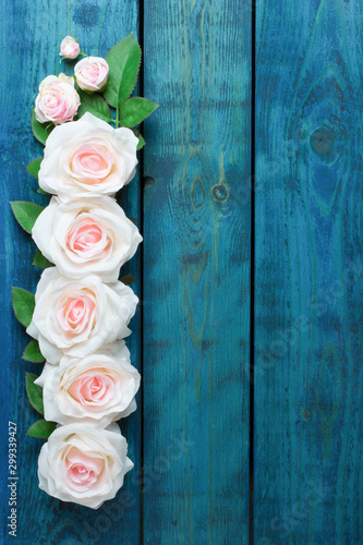 Wedding border with one row of light pink rose flowers on blue wooden background