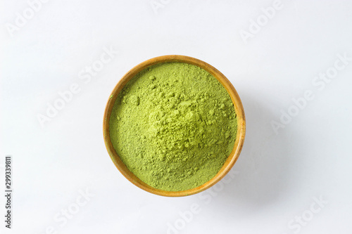 Fotografia Closed up and top view extract Mathcha green tea powder in mini brown wooden bowl on white paper background