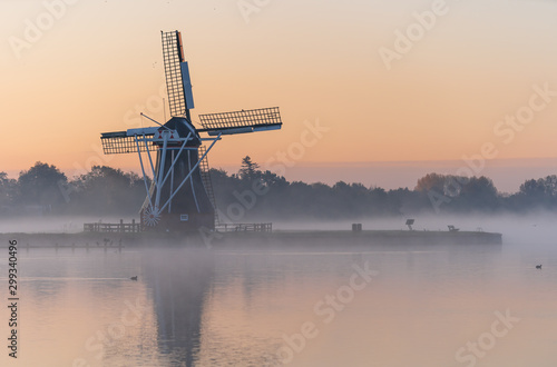 Nature awakens at a traditional Dutch windmill during a foggy sunrise. De Helper, Groningen.