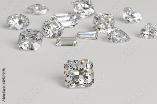 Variously cut diamonds scattered on white background with a radiant cut stone on foreground.