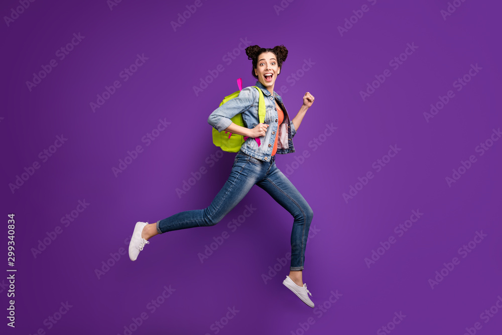Full body profile photo of funny student lady jumping high rushing home after last studying day wear green bag casual denim outfit isolated purple color background Full body profile photo of funny student lady jumping high rushing home after last studying day wear green bag casual denim outfit isolated purple color background