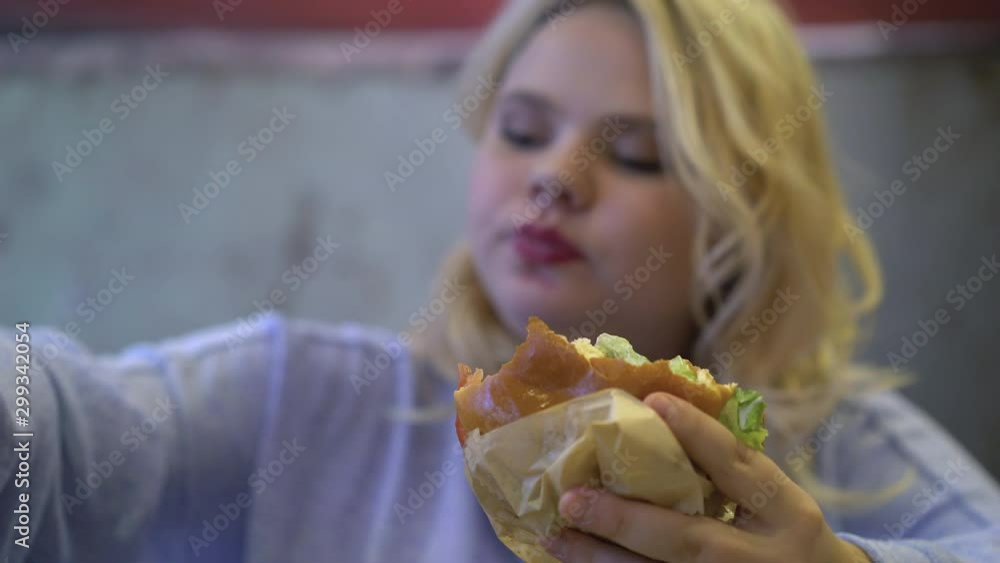 Fast food addict chewing greasy burger young woman having stress eating disorder Fast food addict chewing greasy burger young woman having stress eating disorder