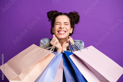 Close up photo of cheerful excited girl go shopping hold many bags feel dream dreamy enjoy her purchases wear denim jeans jacket outfit isolated over violet color background photo