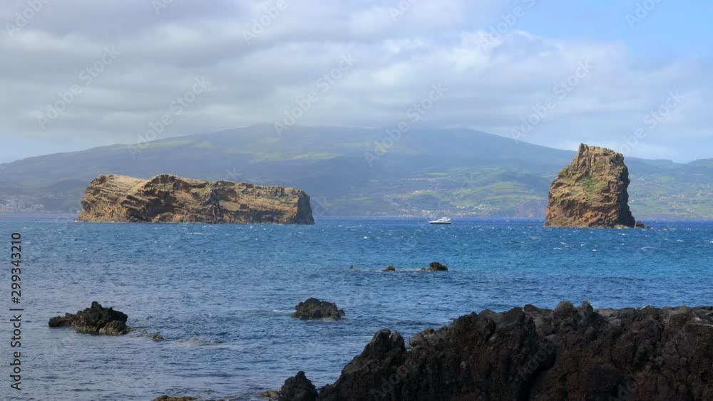 Rocky islets with a iate in the midle and Faial island as background, Pico island, Azores. Rocky islets with a iate in the midle and Faial island as background, Pico island, Azores.