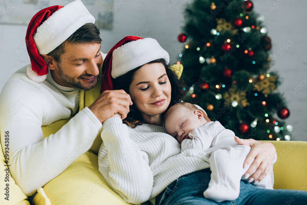 happy man touching hand of smiling wife holding sleeping baby happy man touching hand of smiling wife holding sleeping baby