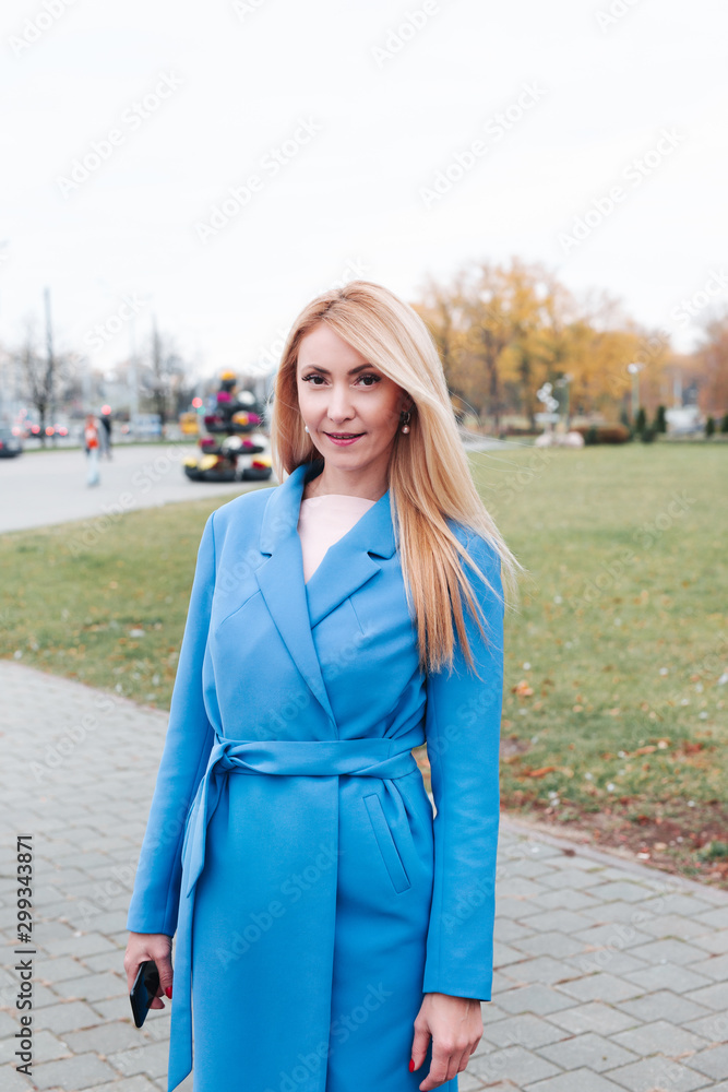 portrait of happy mature blond woman smiling to the camera in autumn park