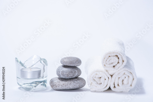 Soft towels  stones and candle for skin care and spa on a white background