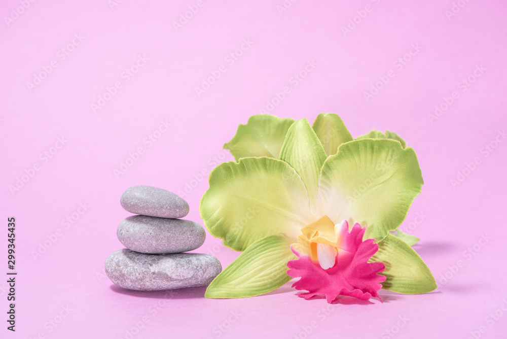 White soft terry towels, orchid, stones and candles for skin care and spa on a pink background White soft terry towels, orchid, stones and candles for skin care and spa on a pink background