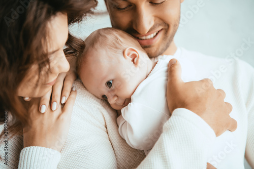 Obraz na płótnie cropped view of happy man holding adorable baby near smiling wife