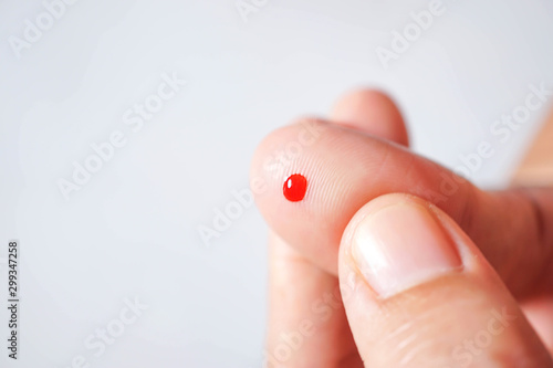 Small drop of red blood on finger..