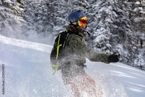 beauty Freerider. snowboarder is riding with snowboard from powder snow hill or mountain forest. Extreme winter sports. off-piste snowboarding in the woods with big swirls of fresh snow in the air