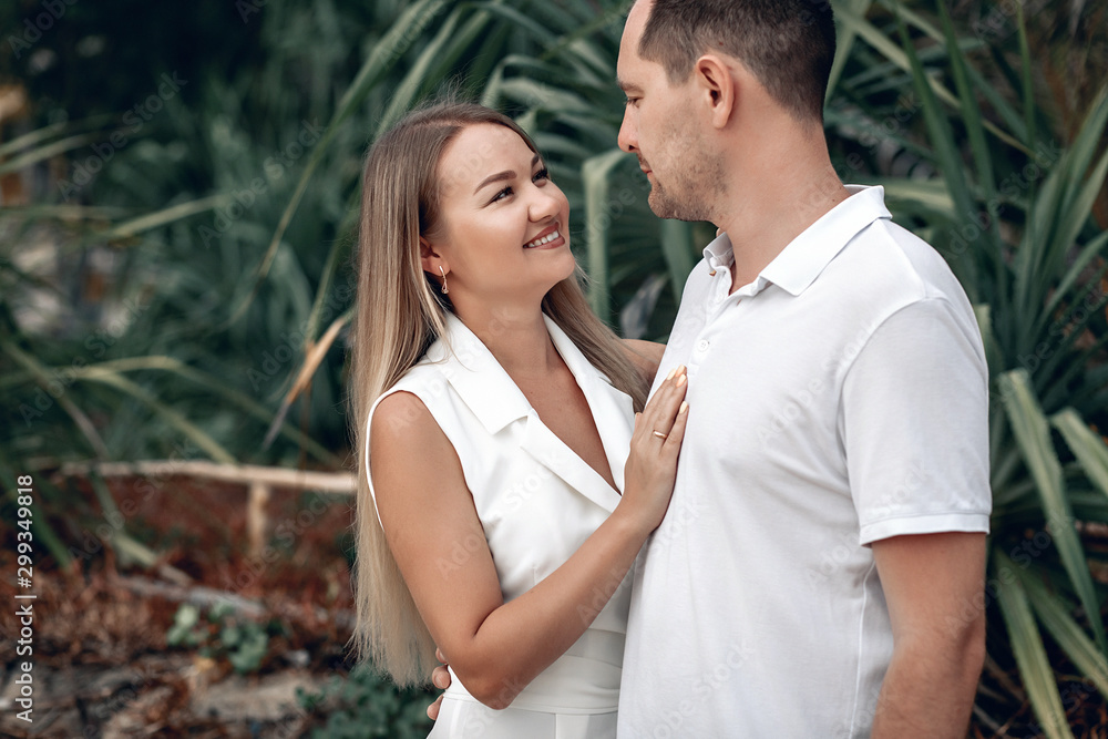 Married couple dressed in white hugging on the beach in Thailand, wife’s hand on man’s chest, both are looking at each other with smile and affection; relationship concept. Married couple dressed in white hugging on the beach in Thailand, wife’s hand on man’s chest, both are looking at each other with smile and affection; relationship concept.