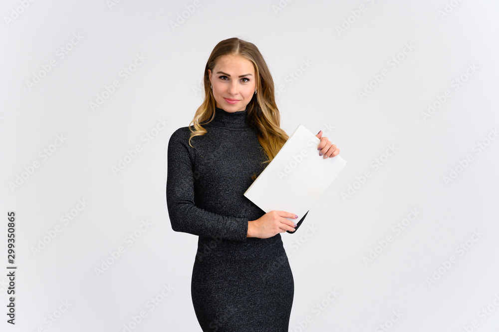 Portrait of a pretty blonde secretary girl with long curly hair in a gray dress standing in the studio on a white background with a folder in her hands with emotions in different poses. Portrait of a pretty blonde secretary girl with long curly hair in a gray dress standing in the studio on a white background with a folder in her hands with emotions in different poses.