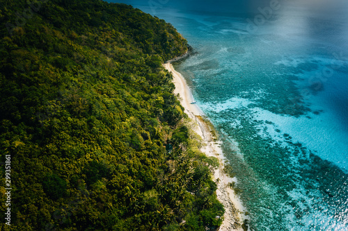 Aerial above view of lonely boat moored at secluded remote tropical uninhabited island with white sand beach, coconut palm trees and turquoise blue shallow lagoon Travel exotic paradise concept