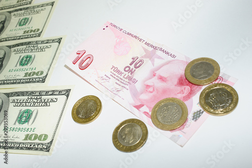 steps of one hundred American dollar bills on which rises a banknote of ten Turkish Lira and Turkish coins Kurush