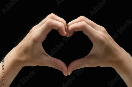 Two hands in the shape of a heart on black isolated background. The concept of love  harmony  caring. Image.