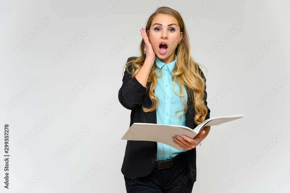 Portrait of a pretty blonde girl financial secretary with long curly hair in a business suit standing in the studio on a white background with emotions in different poses with a folder in his hands. Portrait of a pretty blonde girl financial secretary with long curly hair in a business suit standing in the studio on a white background with emotions in different poses with a folder in his hands.