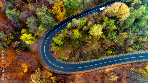 Beautiful aerial landscape of mountain forest road. Aerial view of curvy road in beautiful autumn forest. Top view of roadway with autumn colors