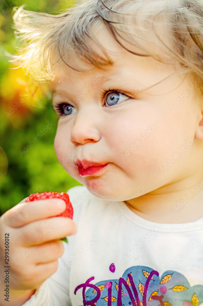 pretty little girl biting into a juicy strawberry pretty little girl biting into a juicy strawberry