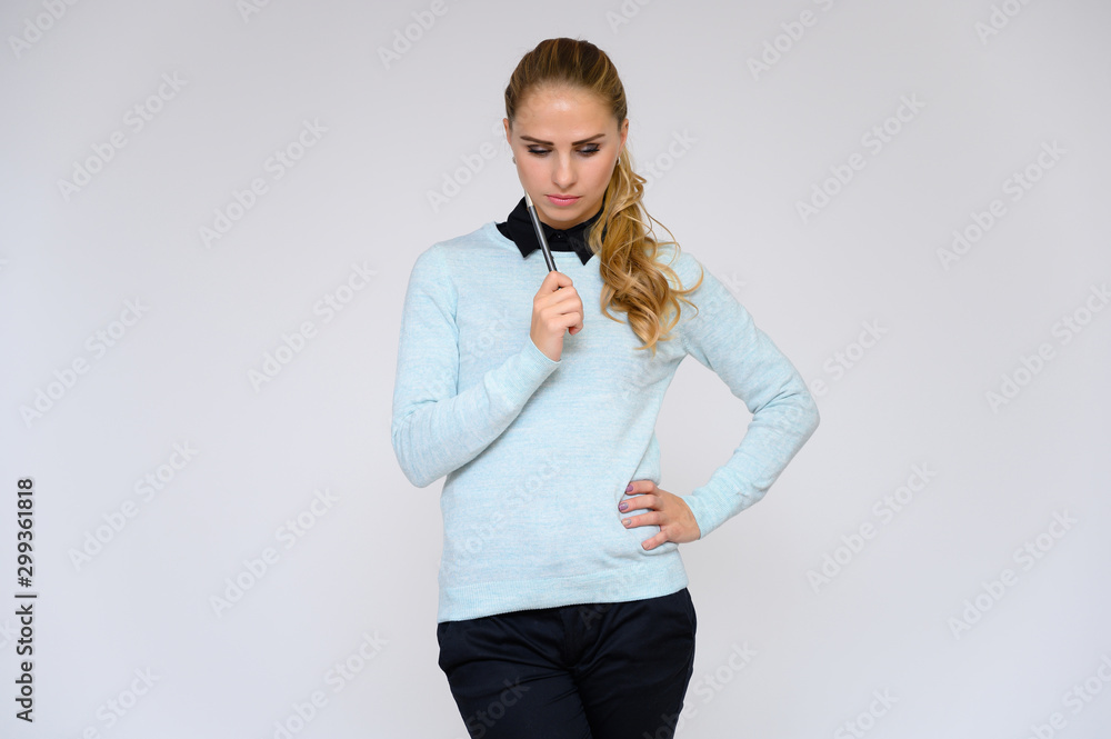 Portrait of a pretty blonde financial secretary girl with long curly hair in a business suit standing in the studio on a white background with emotions in different poses. Portrait of a pretty blonde financial secretary girl with long curly hair in a business suit standing in the studio on a white background with emotions in different poses.