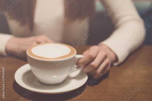 girl with a cup of cappuccino on a wooden table