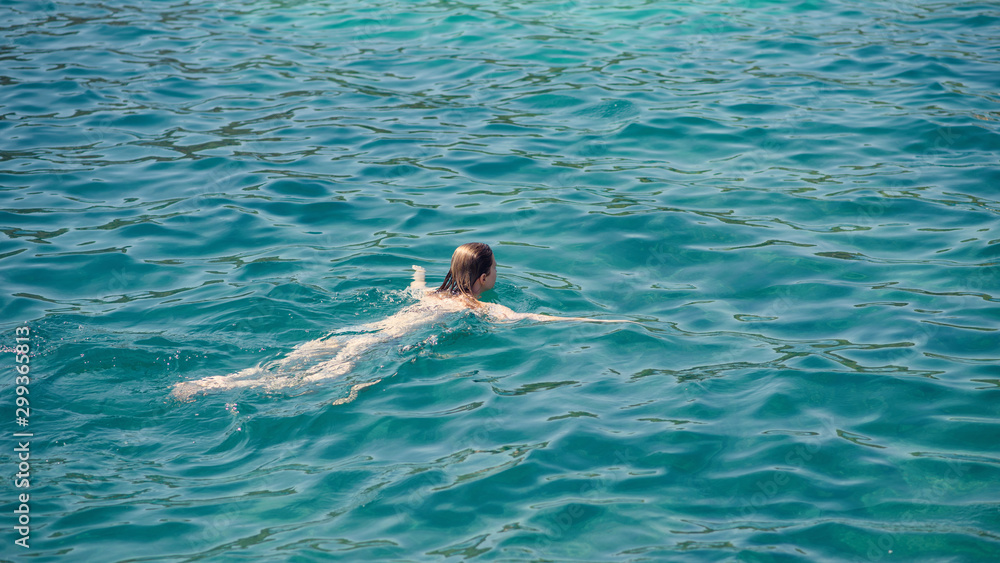 Slender European girl  swimming in ocean during vacations. She relaxing and enjoying her  summer rest.