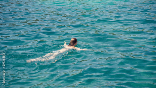 Slender European girl swimming in ocean during vacations. She relaxing and enjoying her summer rest.
