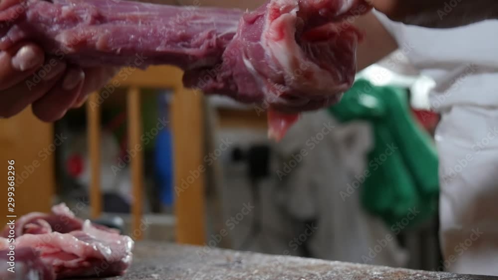Close-up of a butcher's bare hands as she rips away fat from a cut of meat. Close-up of a butcher's bare hands as she rips away fat from a cut of meat.